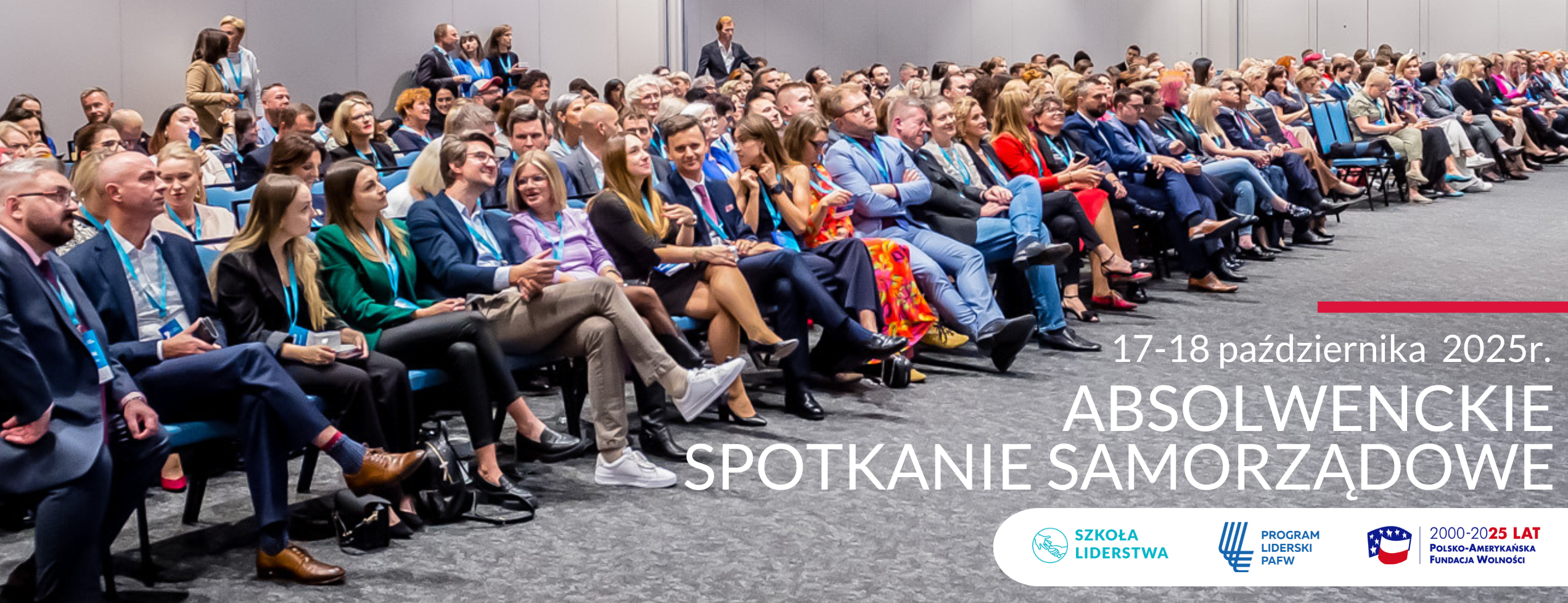Na zdjęciu widoczne są osoby siedzące na krzesłach w dużej sali na konferencji.